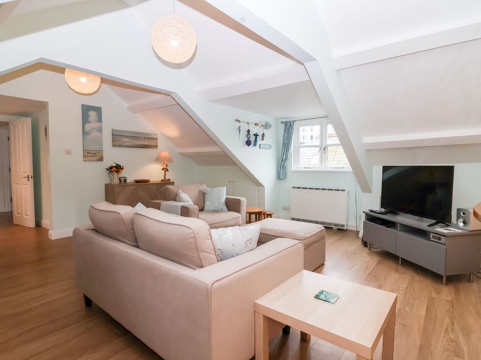 A living room with sofa and TV at Smugglers Loft in Looe