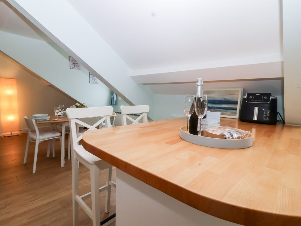 A kitchen with a champagne bottle and glasses on the island at Smugglers Loft in Looe