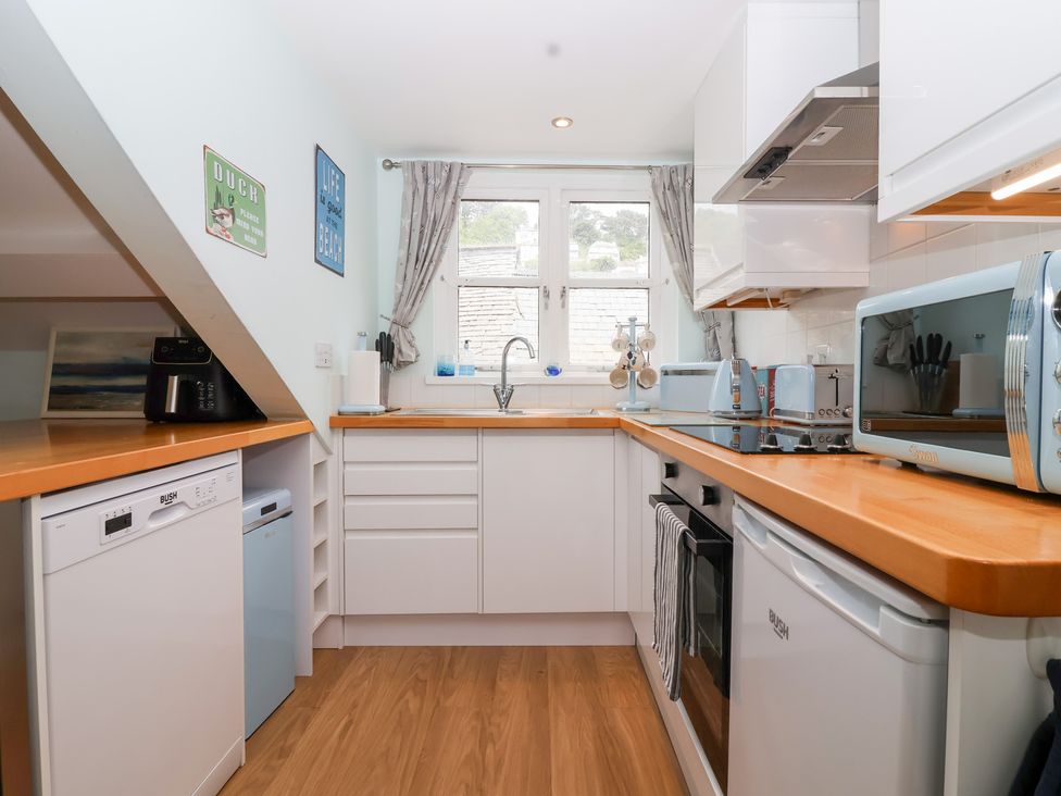 A kitchen with cabinets and appliances at Smugglers Loft in Looe