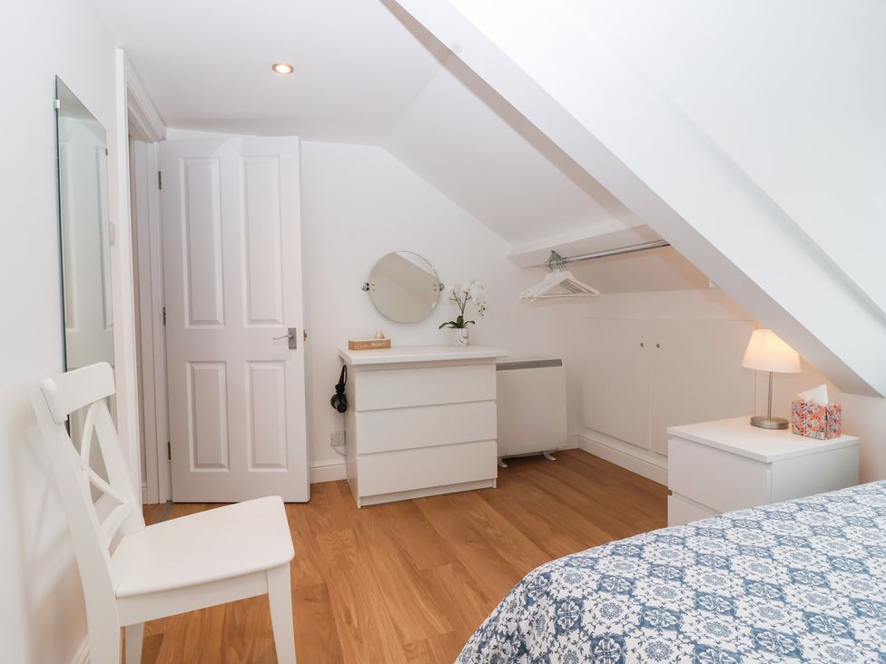 A bedroom with a bed and a mirror at Smugglers Loft in Looe