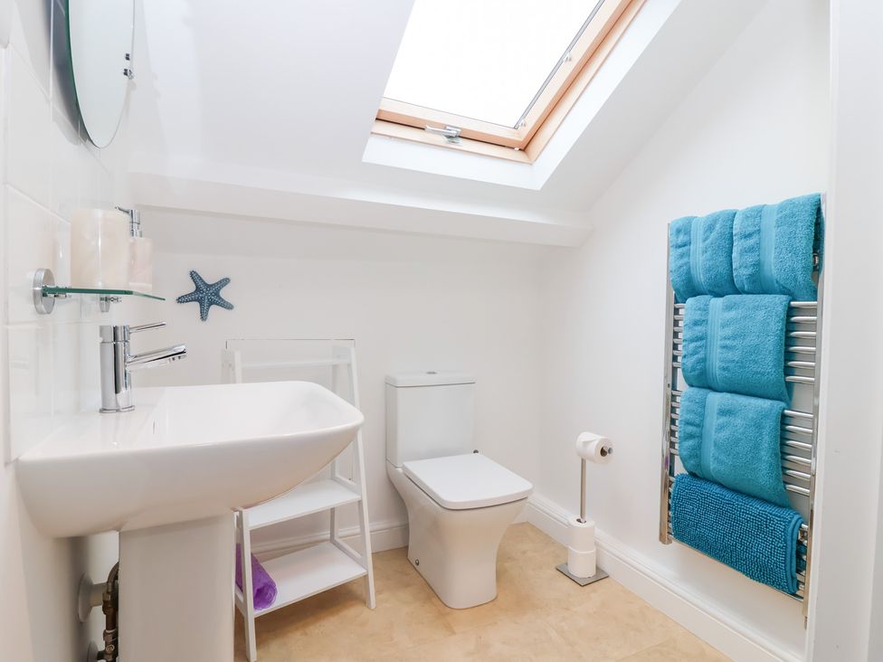 A bathroom with a sink, toilet, and towel rack at Smugglers Loft in Looe