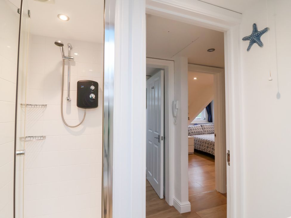 A bathroom with a shower and adjacent bedroom door at Smugglers Loft in Looe