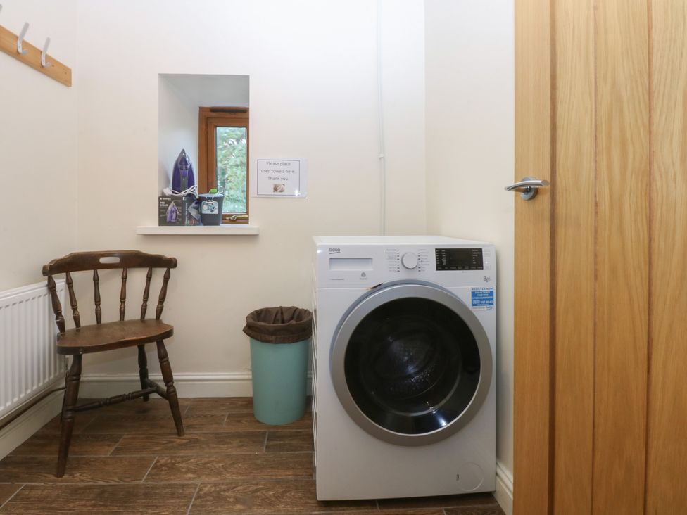 A laundry room with a washing machine and a chair at Llofft Yr Yd Porthmadog
