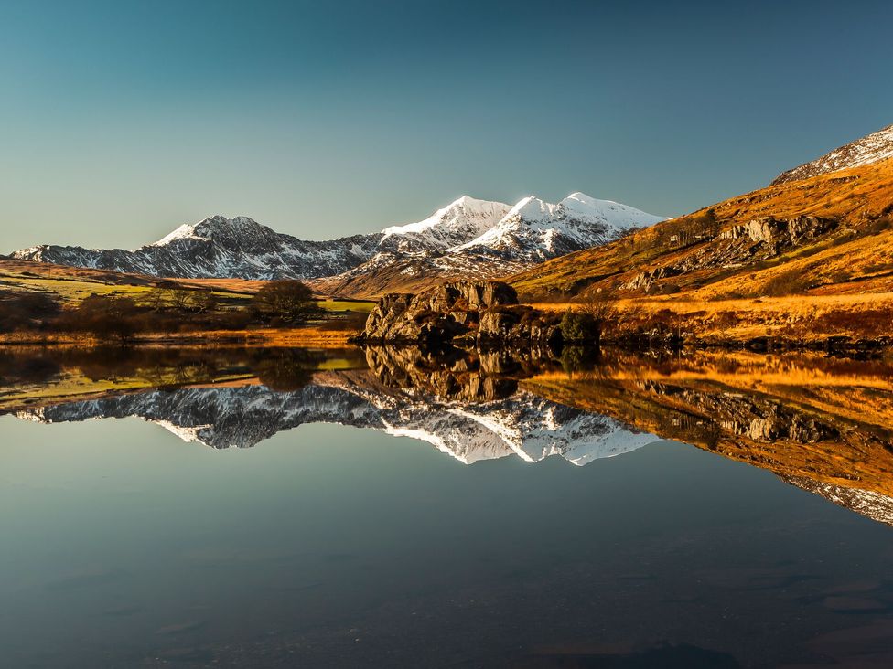 A scenic view of mountains and their reflection in a lake
