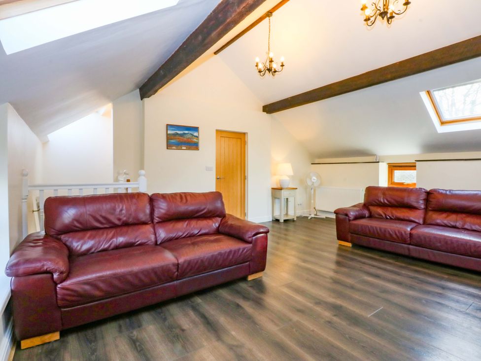 A living room with two sofas and a lamp at Llofft Yr Yd Porthmadog