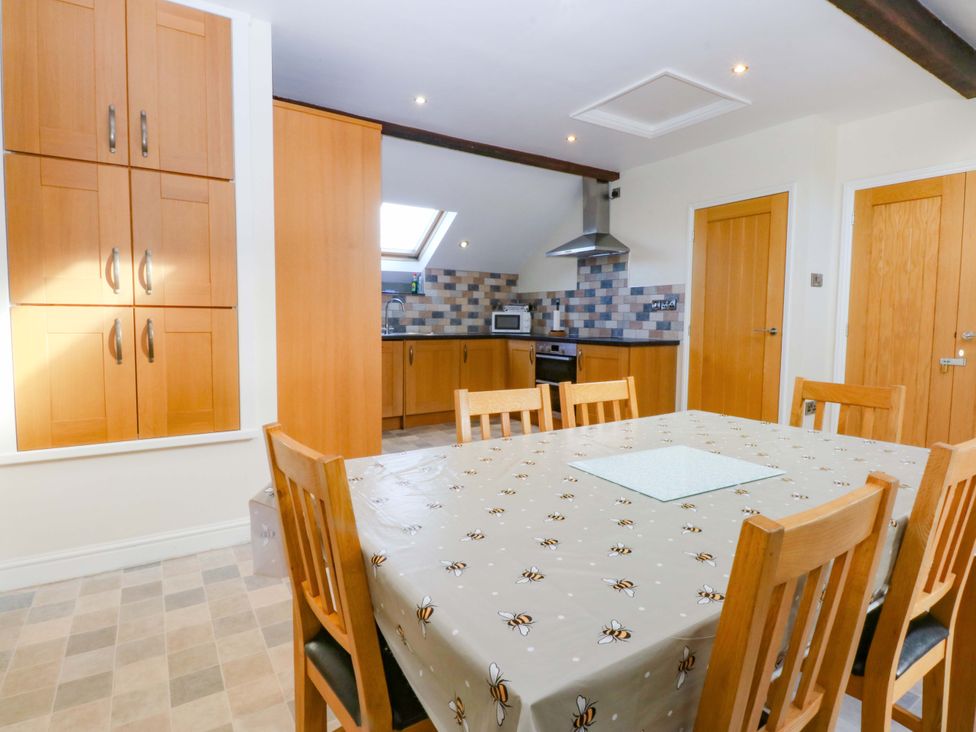 A kitchen with a dining table and chairs at Llofft Yr Yd in Porthmadog