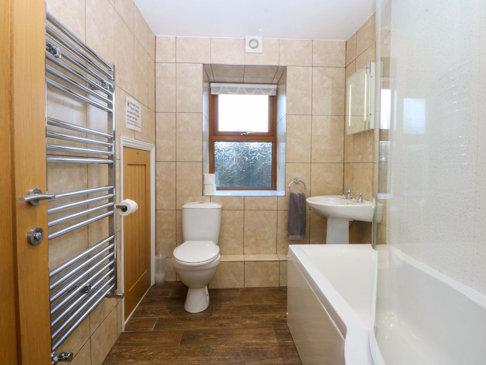 A bathroom with a toilet, sink, and bathtub at Llofft Yr Yd Porthmadog