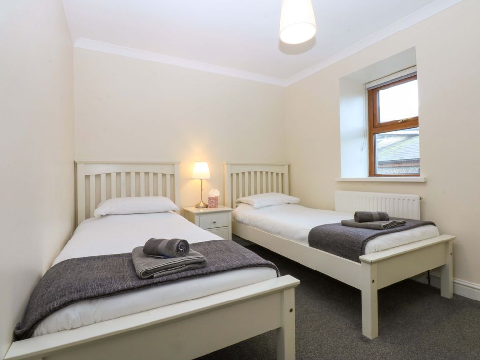 A bedroom with two single beds and a lamp at Llofft Yr Yd in Porthmadog