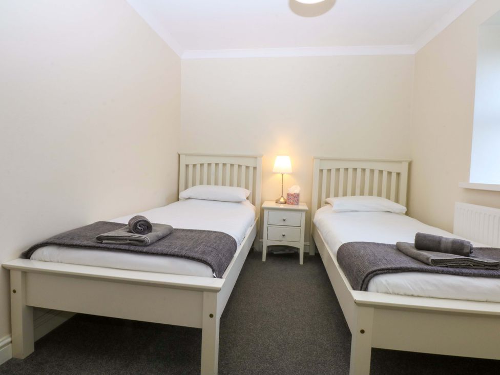 A bedroom with two twin beds and a nightstand at Llofft Yr Yd in Porthmadog