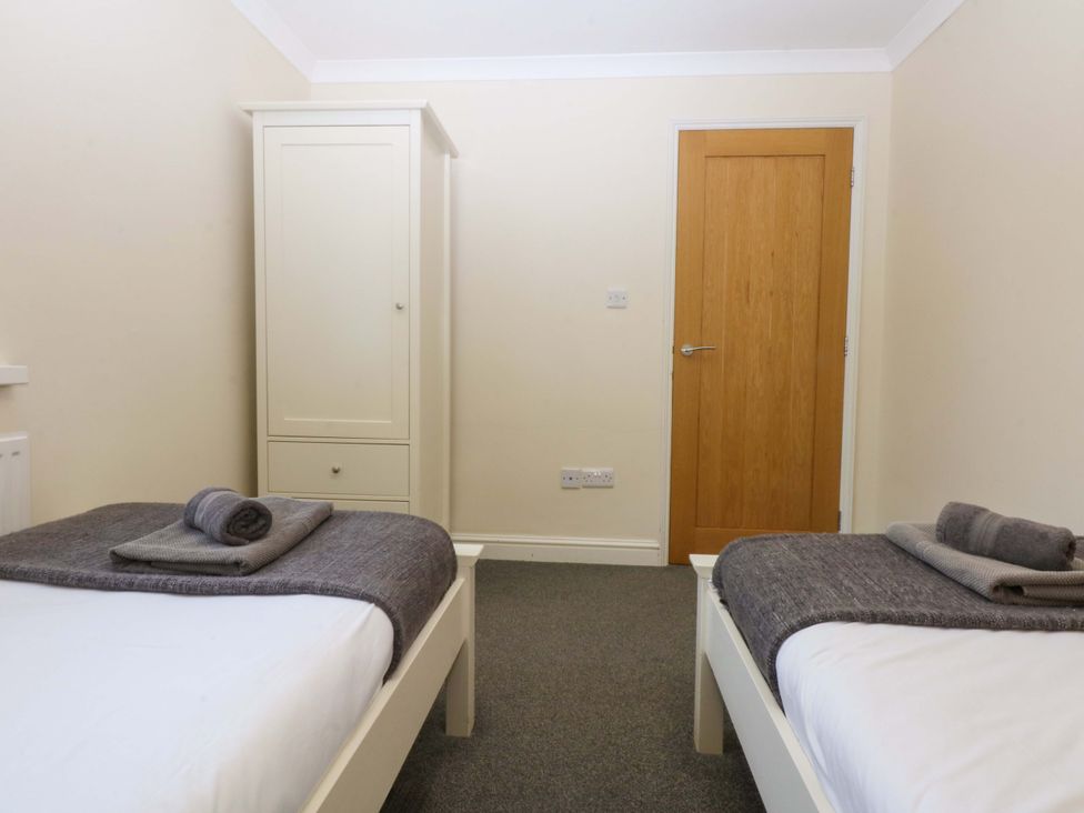 A bedroom with two beds and a wardrobe at Llofft Yr Yd in Porthmadog