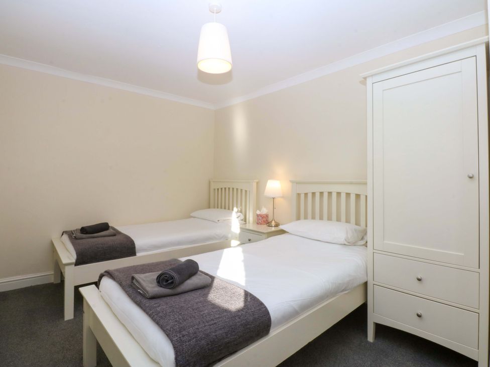 A bedroom with two beds and a wardrobe at Llofft Yr Yd in Porthmadog