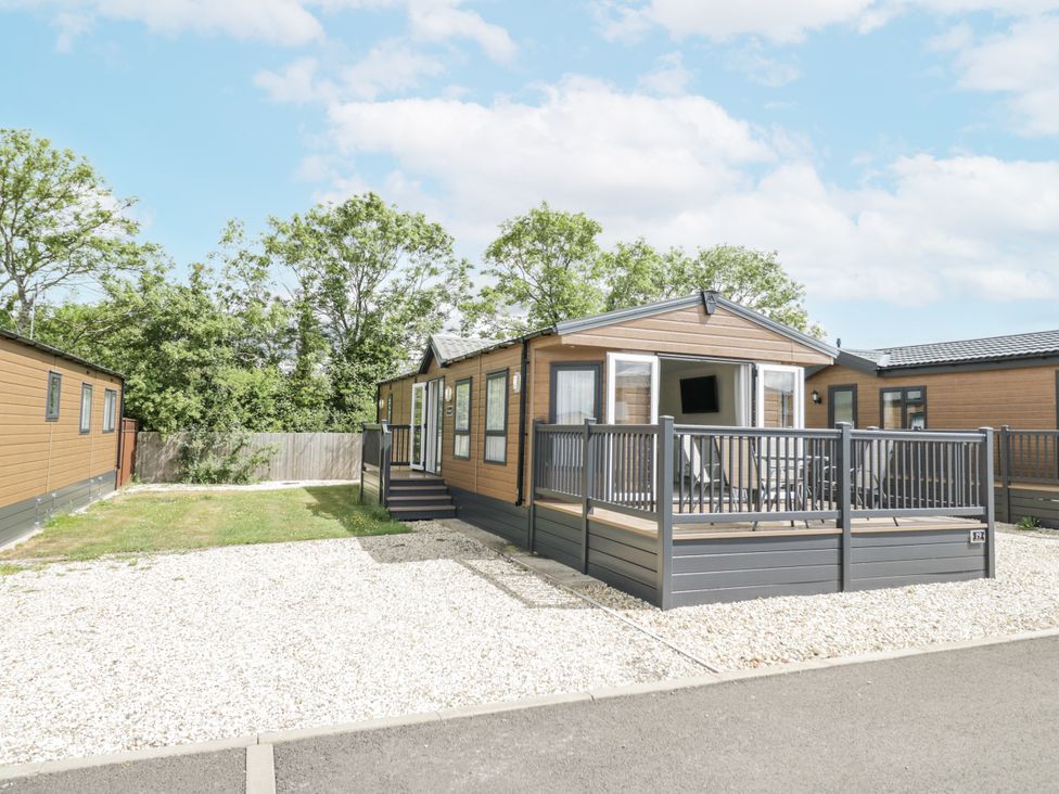 A mobile home with a porch and decking in a gravel area at Serendipity
