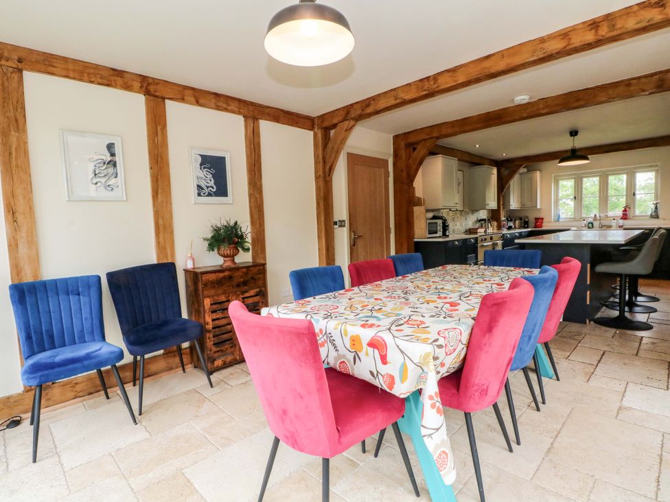 A dining room with a table and chairs leading to a kitchen at Gayton Stables in Heswall