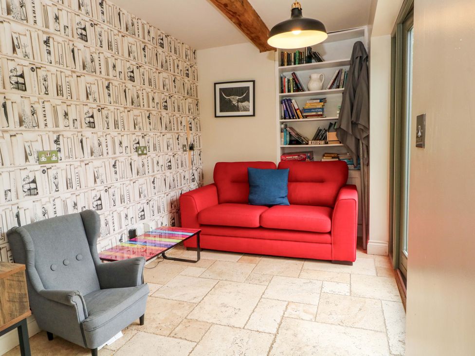 A snug with a red sofa and a bookshelf at Gayton Stables in Heswall
