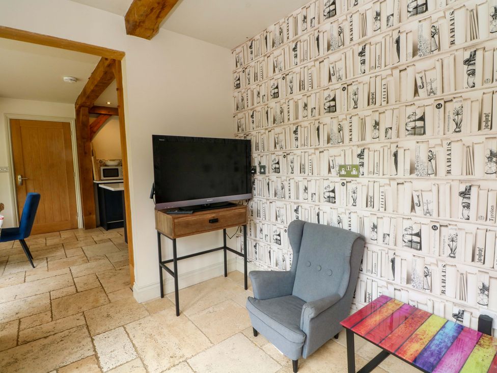 A living room with a television and an armchair at Gayton Stables in Heswall