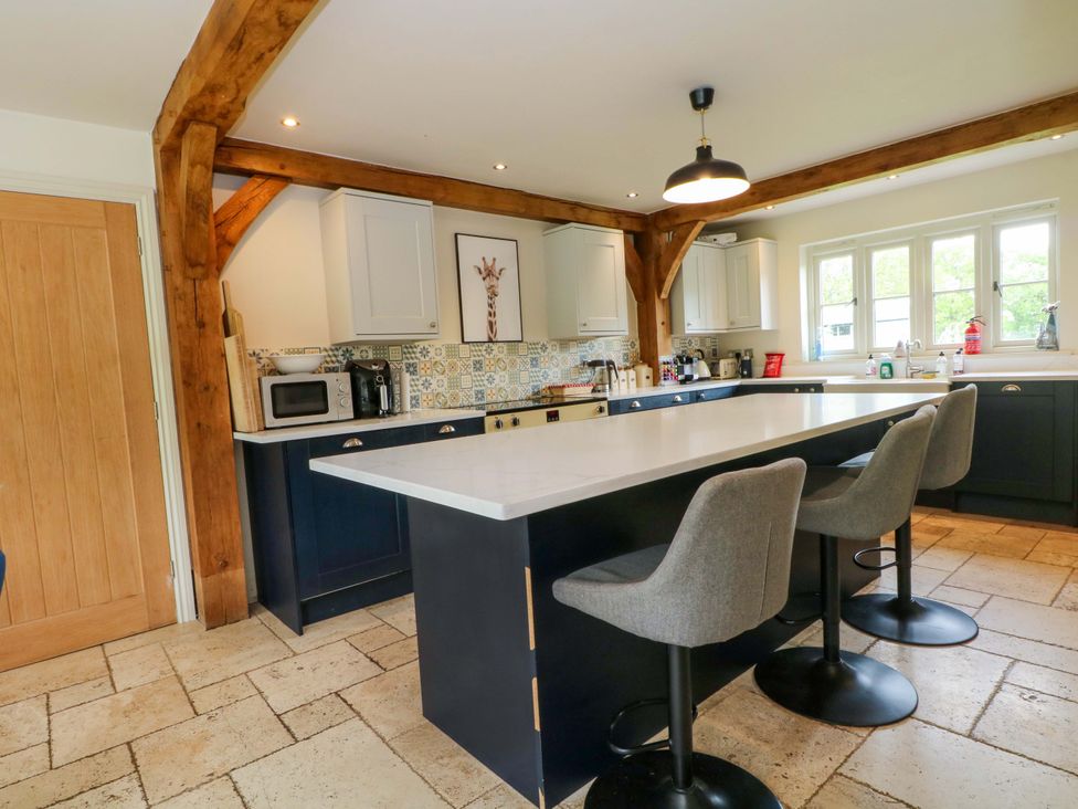 A kitchen with an island and bar stools at Gayton Stables in Heswall