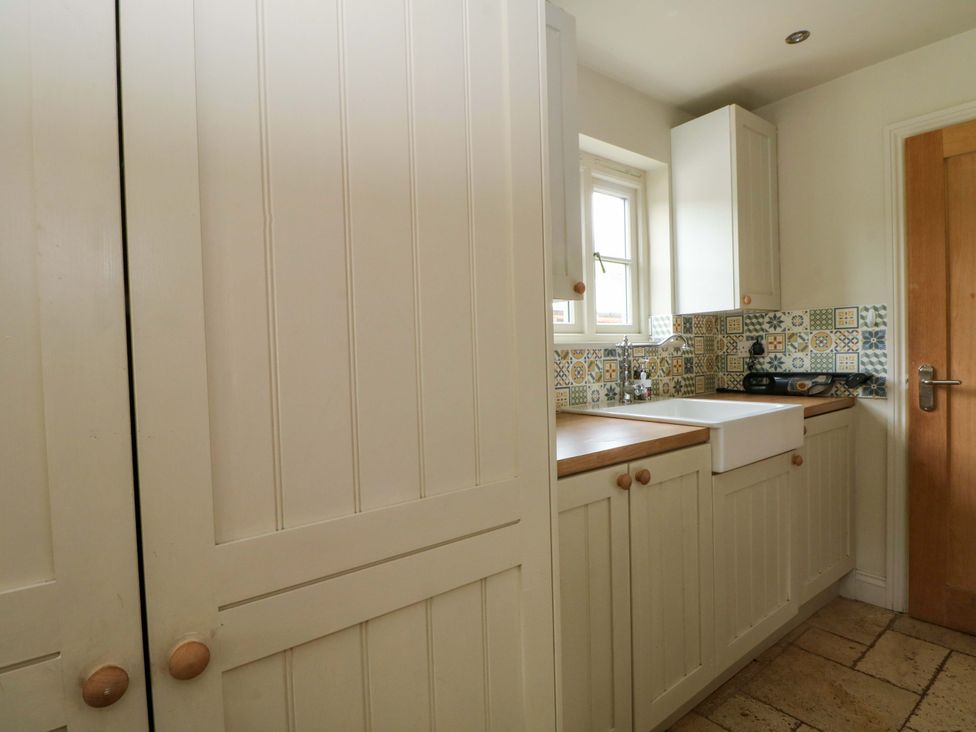 A kitchen with cupboards and sink at Gayton Stables in Heswall