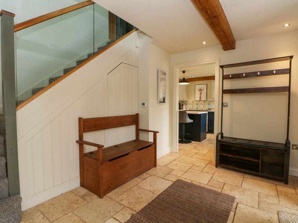 A hallway with a staircase and bench at Gayton Stables in Heswall