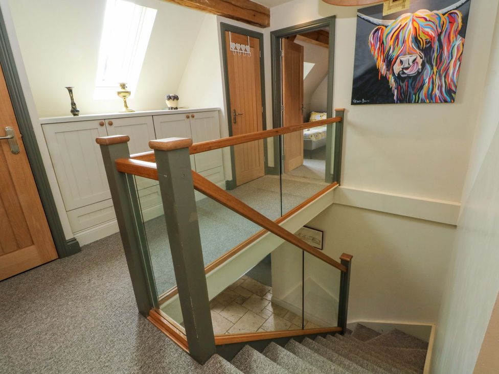 A staircase with a handrail and a cabinet in a hallway at Gayton Stables in Heswall