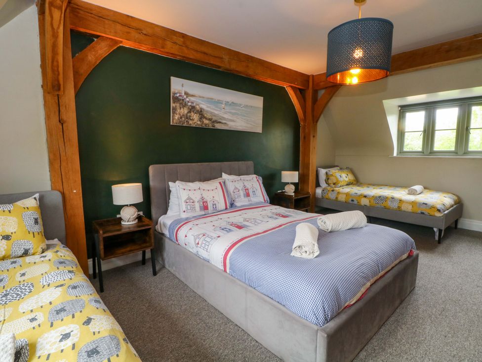 A bedroom with a double bed and single beds at Gayton Stables in Heswall