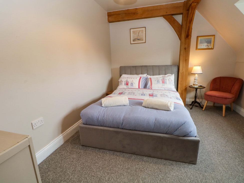 A bedroom with a bed and chair at Gayton Stables in Heswall