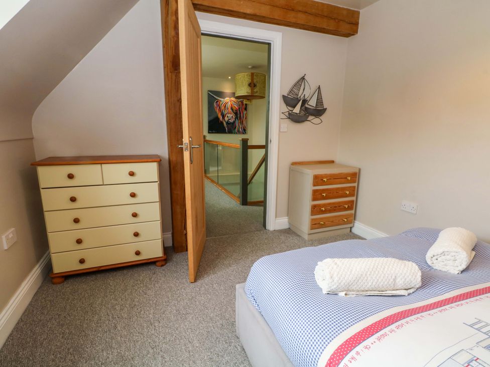 A bedroom with a bed and two drawer units at Gayton Stables in Heswall