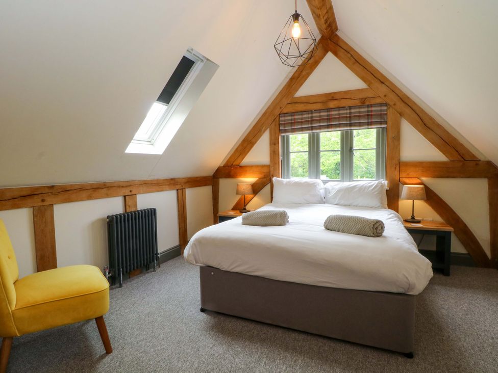 A bedroom with a bed and a chair at Gayton Stables in Heswall