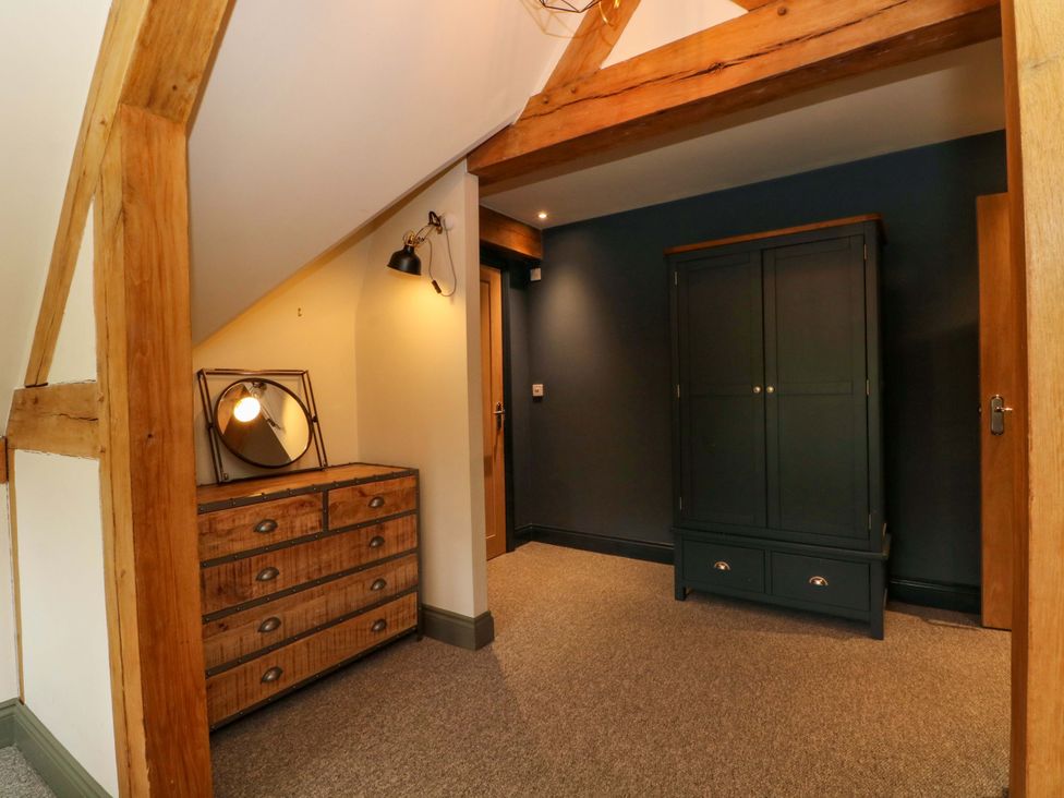 A bedroom with a wardrobe and dresser at Gayton Stables in Heswall