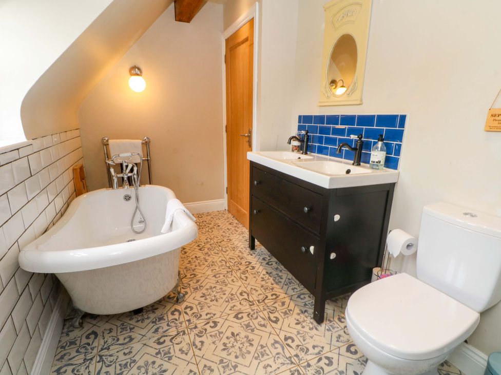A bathroom with a bathtub, toilet, and sink at Gayton Stables in Heswall