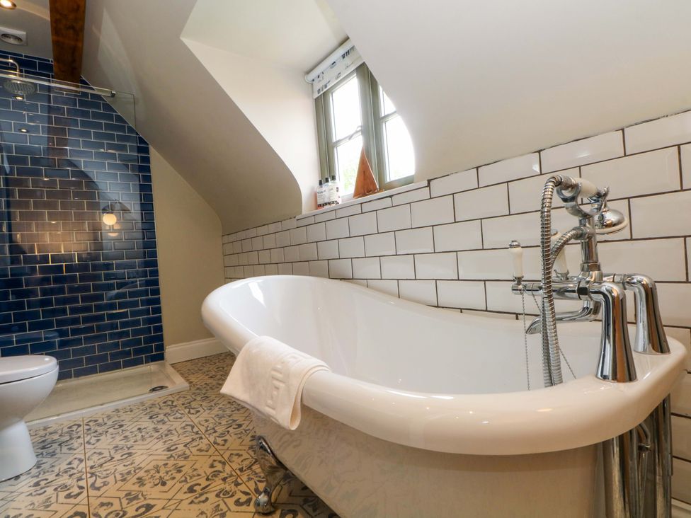 A bathroom with a bathtub and shower at Gayton Stables in Heswall