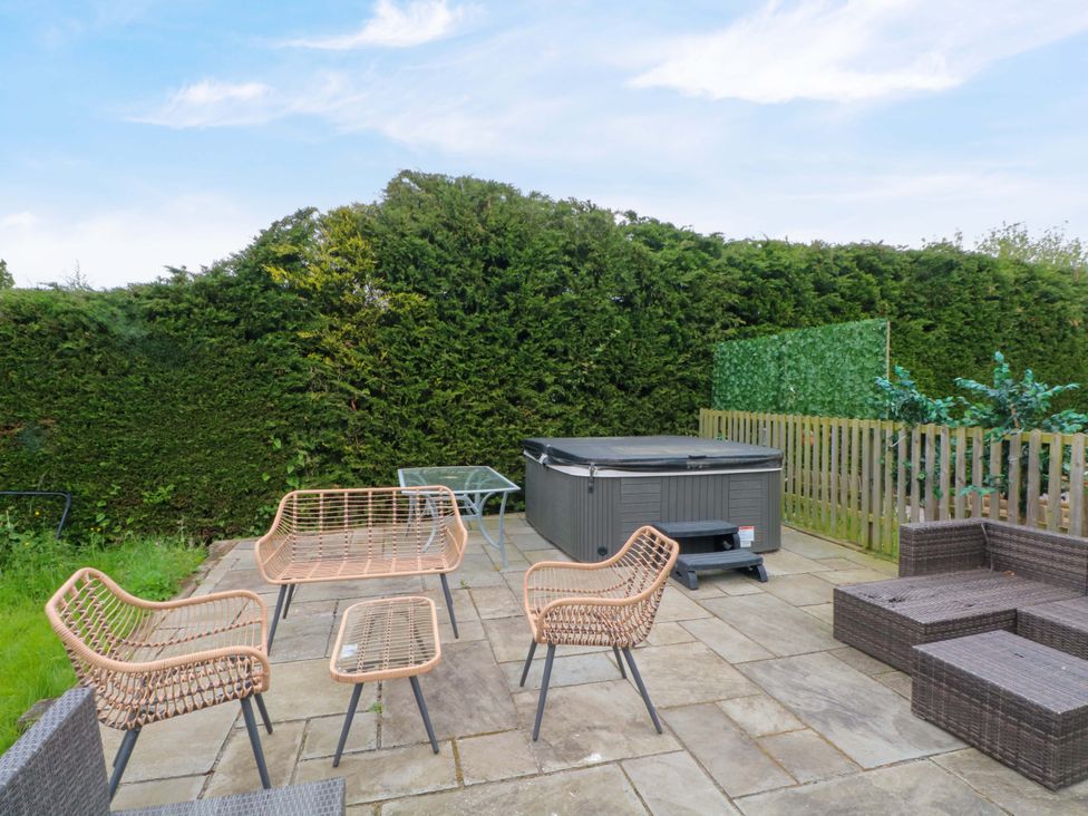 A patio with chairs and a hot tub at Gayton Stables in Heswall