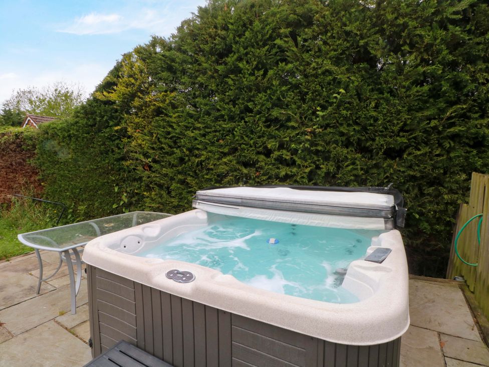 An outdoor space with a hot tub and a table at Gayton Stables in Heswall