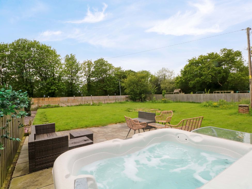 A garden with a hot tub and seating area at Gayton Stables in Heswall