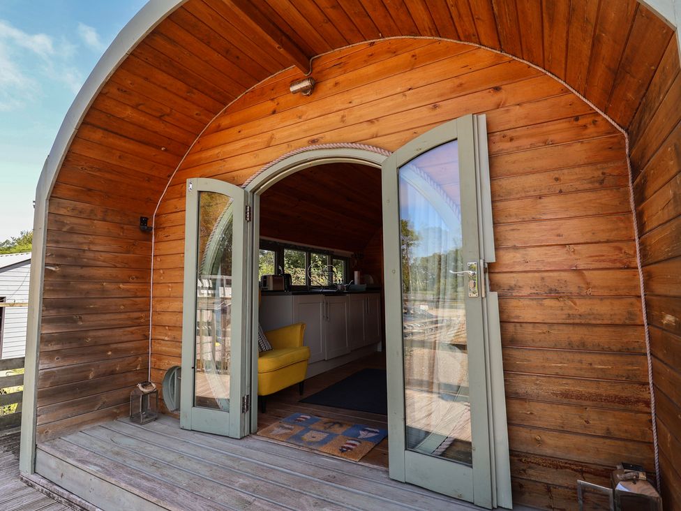 An entrance to a wooden structure with a kitchen area and yellow chair at Gayton Stables in Heswall