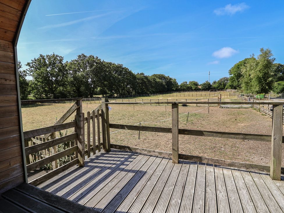A view of a field with a wooden deck and fence at Gayton Stables in Heswall