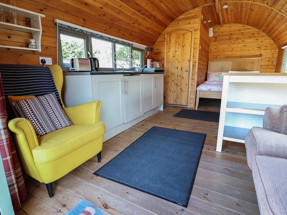 A kitchen and living area with a yellow chair and a sofa at Gayton Stables in Heswall