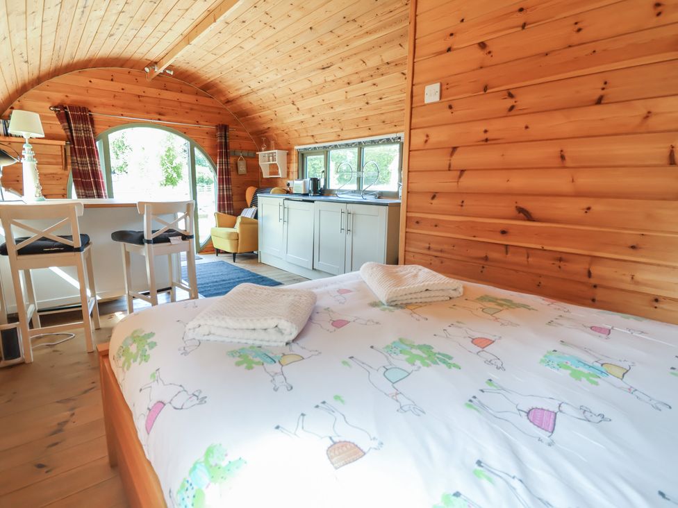 A bedroom with a bed and kitchen area at Gayton Stables in Heswall