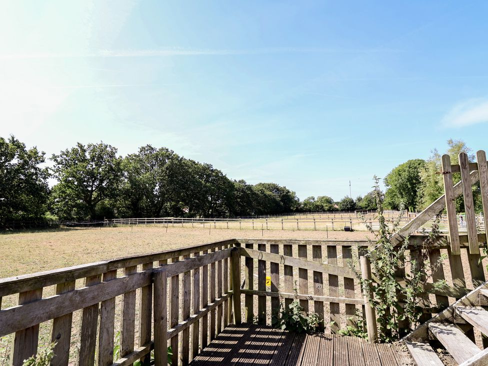An outdoor area with a wooden fence and trees at Gayton Stables in Heswall