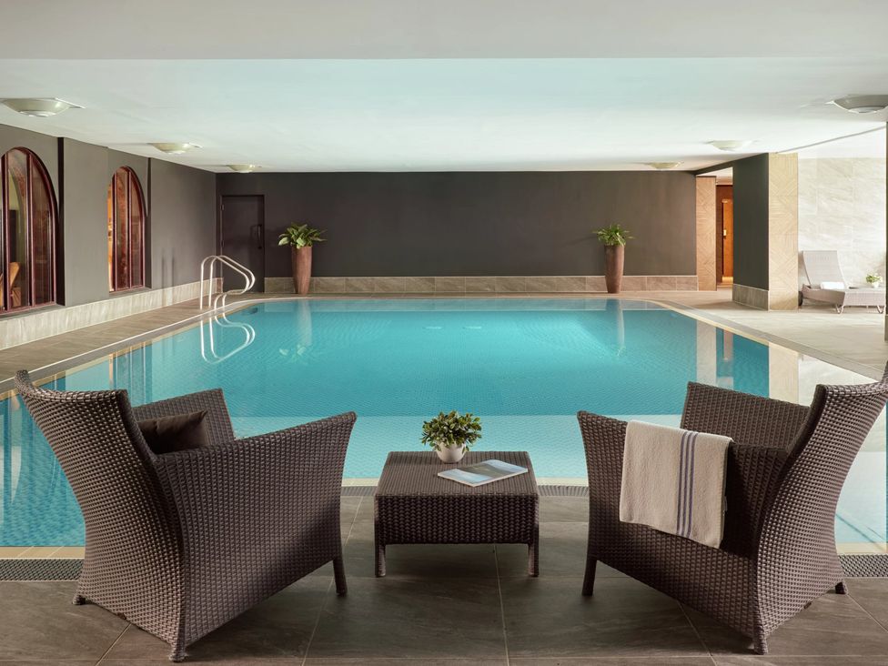 An indoor swimming pool area with chairs and a table at Cosy Corner in the Lakes Greystoke