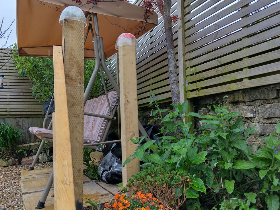 A garden with a swing chair and a parasol at Pound Cottage in Uplyme