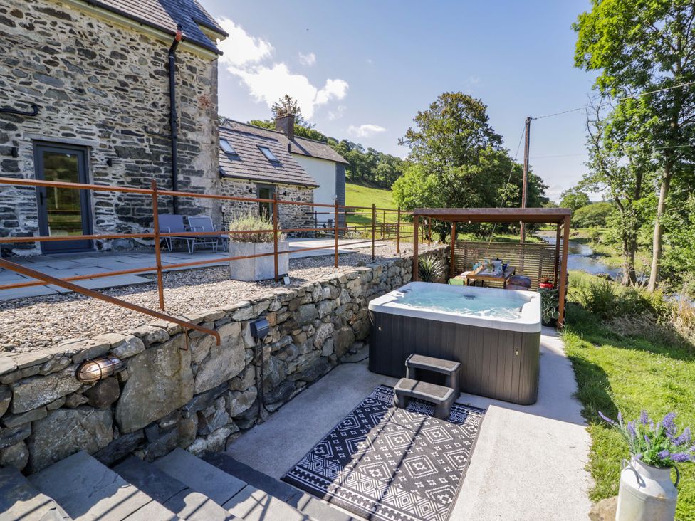 An outdoor area with a hot tub and seating at Plas Glan Yr Afon in Llangernyw