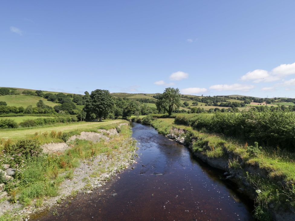 A river flowing through green fields at Plas Glan Yr Afon in Llangernyw