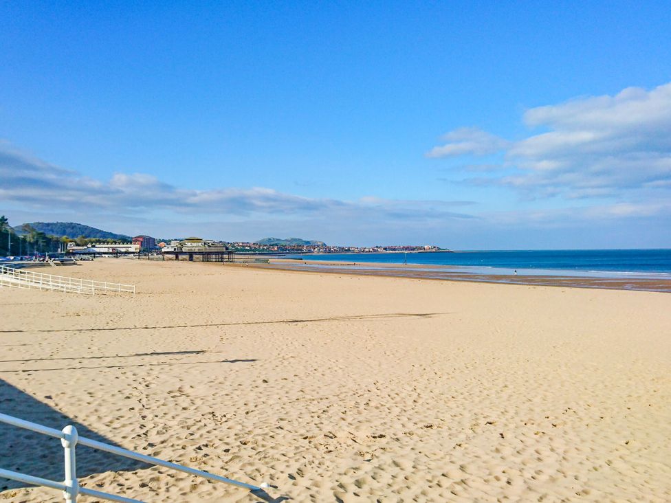 A beach with sand and a pier in the distance at Plas Glan Yr Afon in Llangernyw
