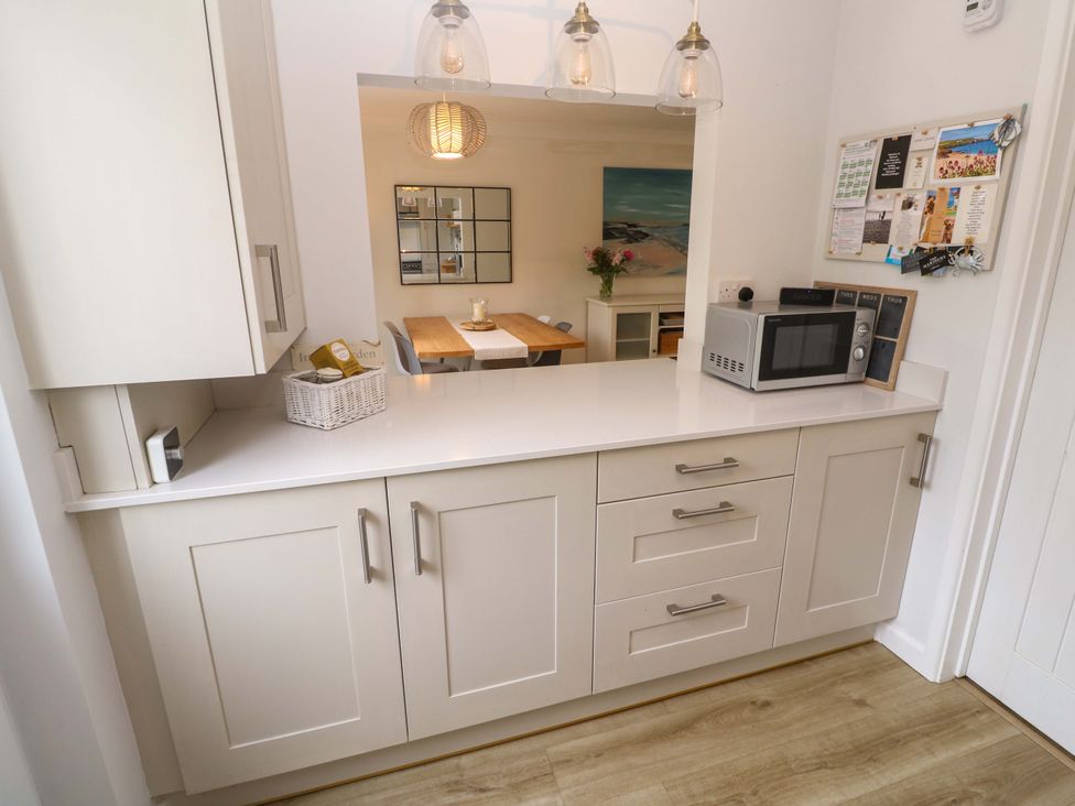 A kitchen with cabinets and a microwave at Trelowen in St Issey near Padstow
