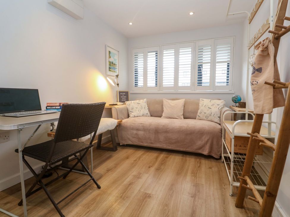 A living room with a sofa, desk and laptop at Trelowen St Issey near Padstow