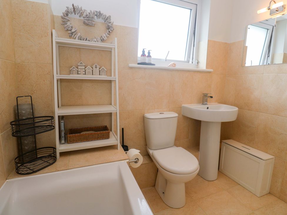 A bathroom with a bathtub, toilet and sink at Trelowen in St Issey near Padstow