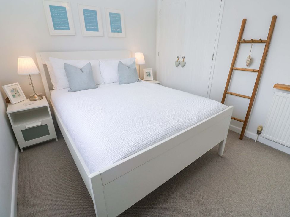 A bedroom with a bed and framed pictures at Trelowen St Issey near Padstow