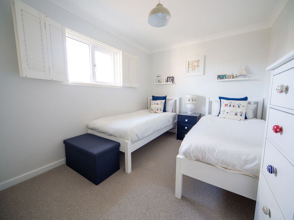 A bedroom with two single beds and a bedside table at Trelowen in St Issey near Padstow