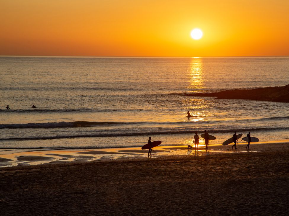 A sunset with surfers on a beach at Trelowen St Issey near Padstow