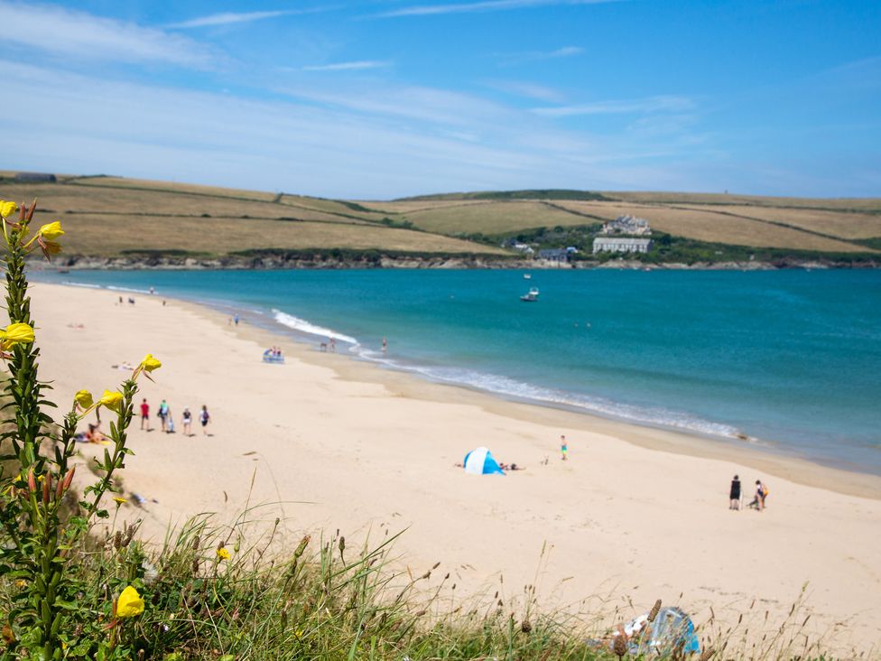 A beach scene with sand, water, and people at Trelowen in St Issey near Padstow